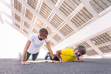 senior sports man laughing funny while training doing push ups with his personal trainer, concept...