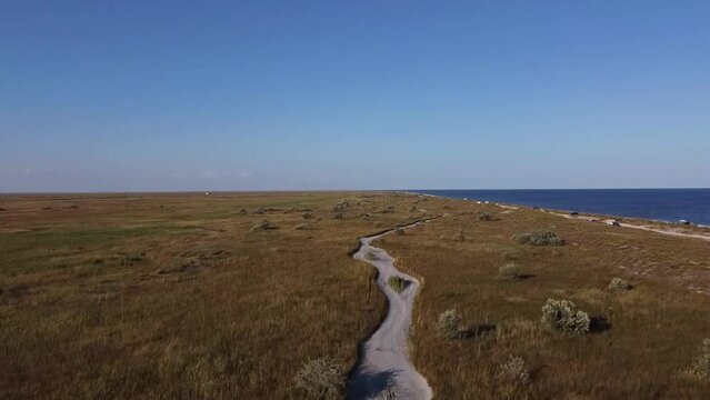 Tilting drone shot revealing the beachfront of Vadu Beach, the clear waters of the Black Sea, and the blue skies in the horizon, located near Constanta County in Romania.