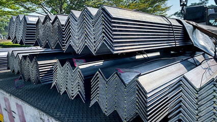 Stacks of angle iron in a factory on shelves in a warehouse Metal profile corners in packs Equal...