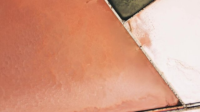 Aerial top down shot of colorful surface of saltern evaporation ponds or saltworks evaporation fields under sun