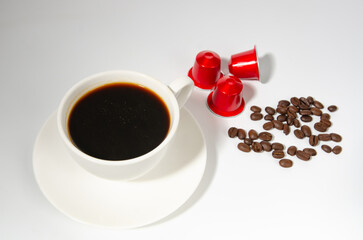 Coffee cup with fresh raw beans and coffee capsules on white background