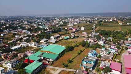 An aerial view of Dehradun, an Indian city during sunrise or sunset, with cloudy weather and rows of residential houses surrounded with greenery.
