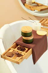 A wooden tray extends over the bathtub, showcasing coffee beans, autumn leaves, two cosmetic jars, a sponge, and a scented candle. Embodying the essence of a tranquil bathroom retreat.