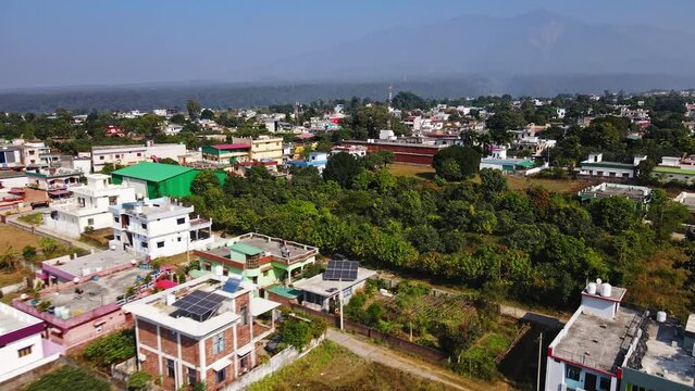 An aerial view of Dehradun, an Indian city during sunrise or sunset, with cloudy weather and rows of residential houses surrounded with greenery.