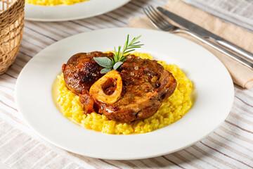 Italian dish Ossobuco meat, specialty of Lombard cuisine of cross-cut beef shanks braised with onion, white wine, and broth. Served with risotto alla milanese, rise made with saffron and cheese.