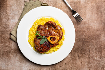 Top view of plate with Italian dish Ossobuco, braised meat served with saffron risotto alla...