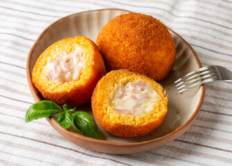 Italian rice balls arancini, that are stuffed, filled with ham prosciutto and mozzarella, coated with breadcrumbs and deep fried.  Sicilian snack, street food. White background.