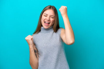 Young Lithuanian woman isolated on blue background celebrating a victory - obrazy, fototapety, plakaty