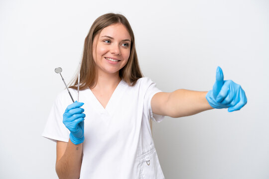 Dentist woman holding tools isolated on white background giving a thumbs up gesture