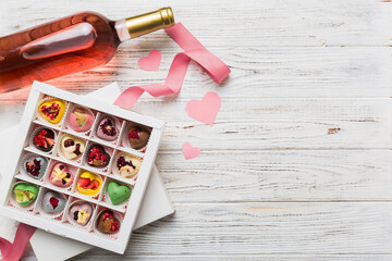 Bottle of red wine on colored background for Valentine Day with gift and chocolate. Heart shaped...