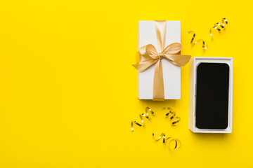 Opened gift box with gold ribbon and smartphone on color background, top view. Blank open box...