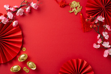 Top view of jubilant setting featuring fans, Feng Shui symbols, auspicious coins, sycee, wall art with a dragon motif, and orchids against a red background, frame for your text or advertising