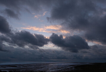 Sea and beach at dusk, the last sunlight on the clouds