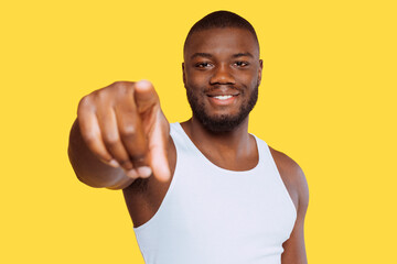 Portrait of a young happy african american man, wears white shirt, pointing finger at camera, at...