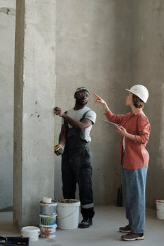 Building contractor giving instructions to coworker at construction site
