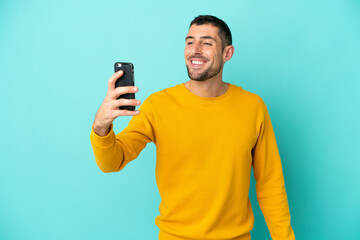 Young handsome caucasian man isolated on blue background making a selfie