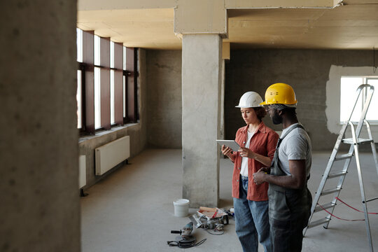Engineer using tablet PC and planning with coworker at construction site