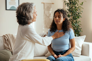 Psychologist teaching breathing exercise to stressed patient in therapy session at home