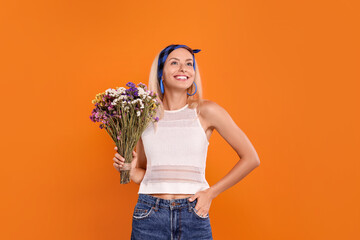 Happy hippie woman with bouquet of flowers on orange background. Space for text