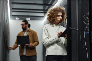 IT engineer using tablet PC with colleague working in background