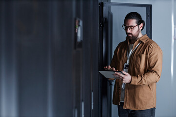 Engineer using tablet PC and working in data center