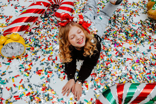 Happy girl lying on confetti with decoration at Christmas