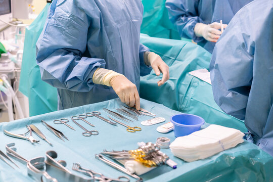 Nurse holding surgical tool with surgeons performing surgery on patient in emergency room