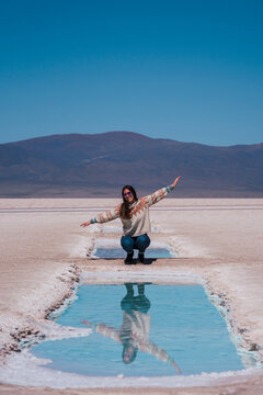 Woman crouching near salt lake in front of mountain