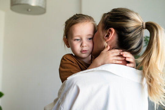 Blond woman embracing and kissing son at home