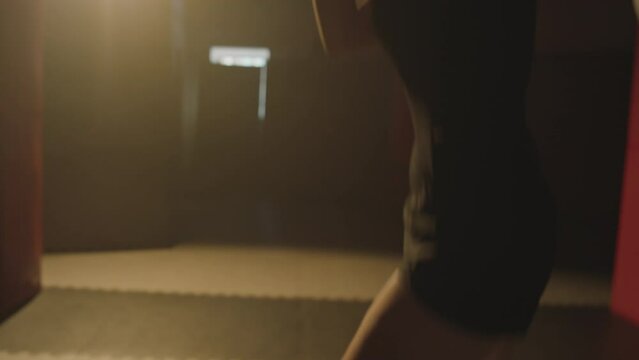 Tilt up shot of woman doing uppercuts while training before competition at boxing gym