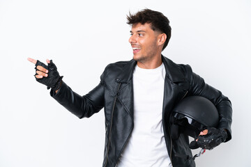 Young caucasian man with a motorcycle helmet isolated on white background pointing finger to the side and presenting a product