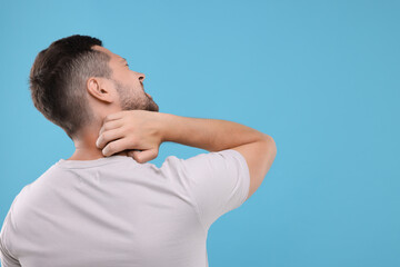 Allergy symptom. Man scratching his neck on light blue background. Space for text