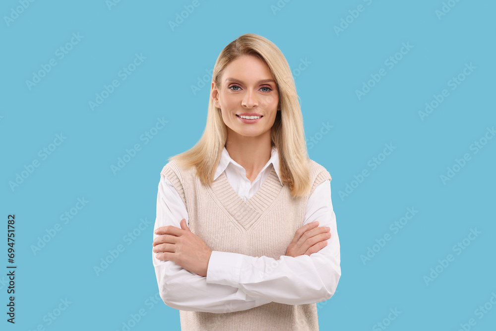 Canvas Prints Portrait of smiling middle aged woman with crossed arms on light blue background