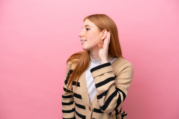 Fototapeta premium Young redhead woman isolated on pink background listening to something by putting hand on the ear