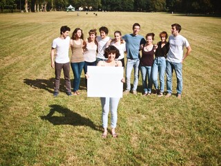Group of friends in a park holding a white sign