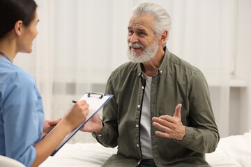 Obraz premium Smiling elderly patient talking with nurse in hospital