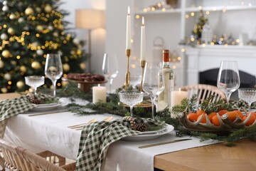 Christmas table setting with festive decor and dishware in room