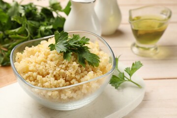 Delicious bulgur with parsley in bowl on table, closeup