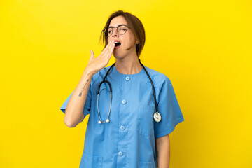 Surgeon doctor woman isolated on yellow background yawning and covering wide open mouth with hand