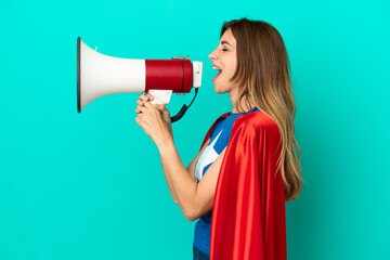 Super Hero caucasian woman isolated on blue background shouting through a megaphone