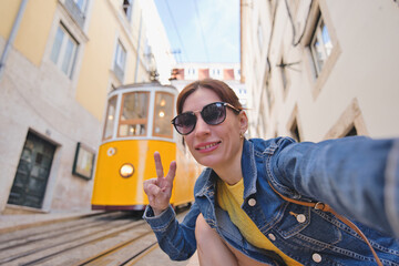 Woman tourist with famous yellow funicular tram of Lisbon, Portugal - Tourist attraction - Europe destinations lifestyle concept - obrazy, fototapety, plakaty
