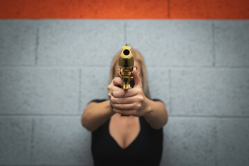 A girl takes aim from a golden Desert Eagle pistol, soft focus photo.