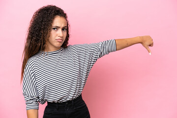 Young hispanic woman isolated on pink background showing thumb down with negative expression