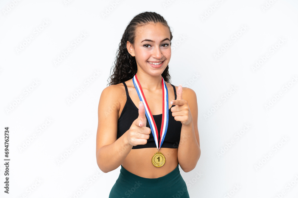 Wall mural young sport woman with medals isolated on white background pointing to the front and smiling