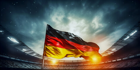 Waving national flag of Germany above blurred football arena in front of dramatic sky.
