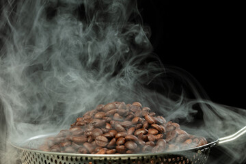 Roasted Coffee seeds with smoke. Beans Coffee roasted on pile and hot smoke raise up in line shape....