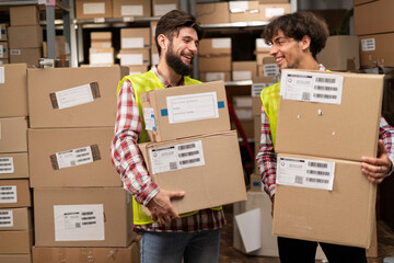 Two mixed race warehouse workers preparing a shipment in a large warehouse. Logistics employees...