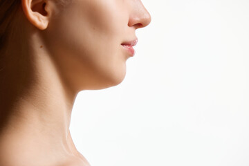 Cropped side view image of female face, neck isolated against white studio background. Reduction of double chin.