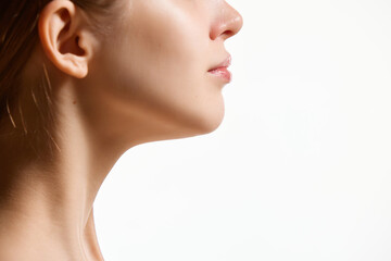 Cropped side view image of female face, neck isolated against white studio background. Reduction of double chin. - obrazy, fototapety, plakaty