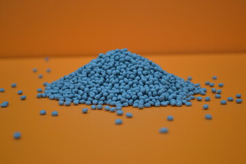 A small pile of gray pellets on an orange background